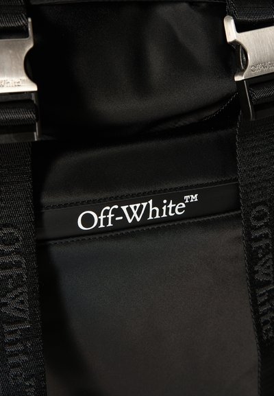 Intérieur de sac noir avec logo "Off-White™" blanc sur une bande de tissu et sangles noires réglables avec boucles en métal.