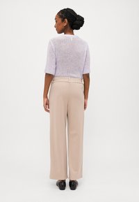 Light purple knit sweater with short sleeves, paired with beige wide-leg pants. The outfit features a textured fabric and a simple design.
