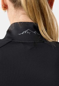 Maglietta sportiva nera con colletto alto e tessuto strutturato. Presenta un design con silhouette di montagna grigia nella zona del collo sul retro.