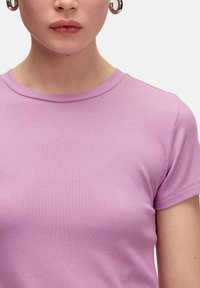 Lichtpaarse, geribde t-shirt met een ronde hals en korte mouwen. De stof heeft een gladde textuur en een aansluitend ontwerp met nette stiksels.