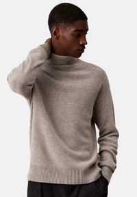 Maglione a collo alto in maglia grigio chiaro con polsini e orlo a coste, caratterizzato da un tessuto testurizzato e una vestibilità comoda.