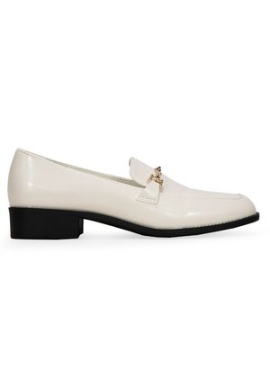 Mocasines de charol blanco con un tacón negro bajo. Presentan un detalle decorativo de hardware dorado en la parte frontal y un diseño de punta afilada.