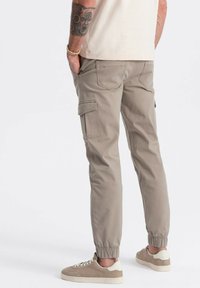 Cargo joggers van lichtbeige katoen met zijzakken en elastische boorden. Gecombineerd met crèmekleurige sneakers, wat zorgt voor een casual look.