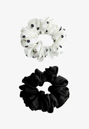 Zwei Stoff-Haargummis, eines weiß mit schwarzen Punkten und eines in einfarbigem Schwarz, auf weißem Hintergrund präsentiert.