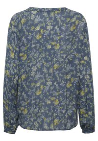 Blouse à fleurs bleues avec des manches longues, présentant un tissu texturé, des motifs de fleurs jaunes et violettes, et une coupe décontractée.