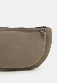 Borsetta grigia in camoscio con chiusura a zip, forma arrotondata e texture liscia, dotata di accessori metallici per la durabilità.