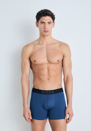 Boxeri scurți de culoare albastră închisă, cu un brâu elastic negru ce prezintă în mod proeminent numele mărcii "BOSS". Textură de material neted, design ajustat.