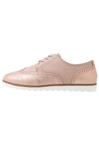 Vaaleanpunainen nahkakenkä, jossa on sileä ja teksturoitu pinta, brogue-yksityiskohdat ja valkoinen kumipohja. Varustettu yksinkertaisella nauhakiinnityksellä.