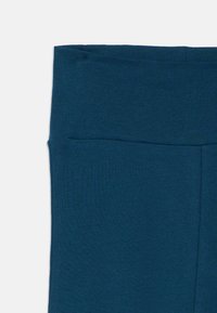 Leggings azul marino con una textura suave y elástica y una cinturilla alta elástica. Sin costuras ni patrones visibles, adecuados para ropa de actividad.