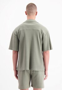 Olijfgroene shirt met korte mouwen en bijpassende shorts gemaakt van textuurstof. Met een ruime pasvorm en eenvoudig kraagontwerp.