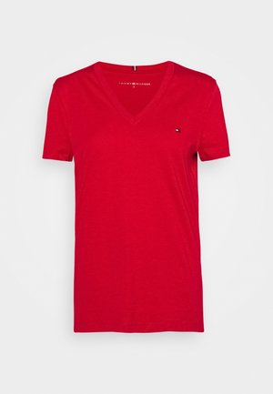 Czerwona koszulka z krótkim rękawem i dekoltem w serek z małym logo Tommy Hilfiger na lewej piersi, rozmiar mały, na jednolitym jasnym tle.