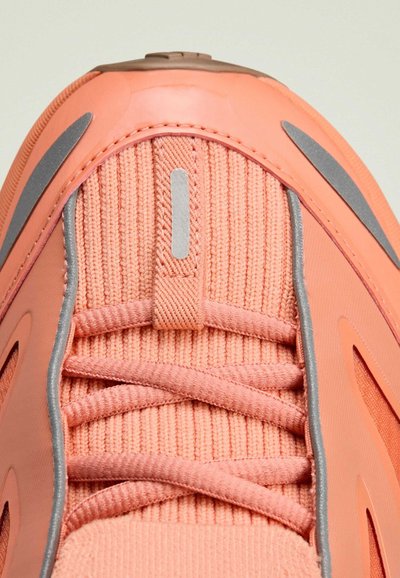 Baskets roses avec une tige en tissu texturé, des lacets plats, et des détails argentés. Talon en caoutchouc lisse et bout renforcé.