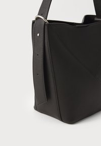 Melnas ādas plecu soma ar ģeometrisku dizainu, teksturētu apdari un noņemamu siksnu ar sudraba krāsas apdari.