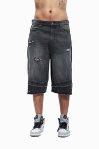 Sorte denimshorts med slidte detaljer, frynset kant og lommer, iført grå og hvide sneakers. Glat tekstur.