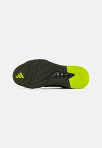 Sole di scarpa Adidas, caratterizzata da una base in gomma testurizzata di colore verde scuro con un accento giallo brillante, motivo a reticolo e marchio "TRAXION".