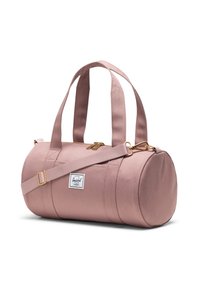 Vä pinki sylindrisk duffelväska med dubbla handtag, justerbar axelrem, gyllene dragkedjor och en liten vit rektangulär varumärkesetikett på sidan.