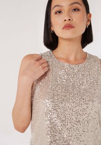 Top senza maniche in argento chiaro, decorato con paillettes scintillanti disposte in righe verticali, con scollatura rotonda e texture liscia.