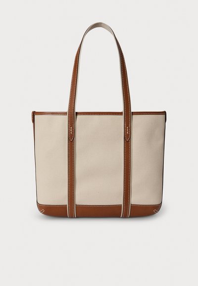 Τσάντα tote από καμβά σε κρεμ χρώμα με καφέ δερμάτινες λεπτομέρειες· διαθέτει δύο ανθεκτικές λαβές και αντίθετη ραφή κατά μήκος των άκρων.