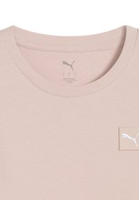 Light pink t-shirt with a round neckline, made from soft fabric. Features a small white Puma logo patch on the left side.