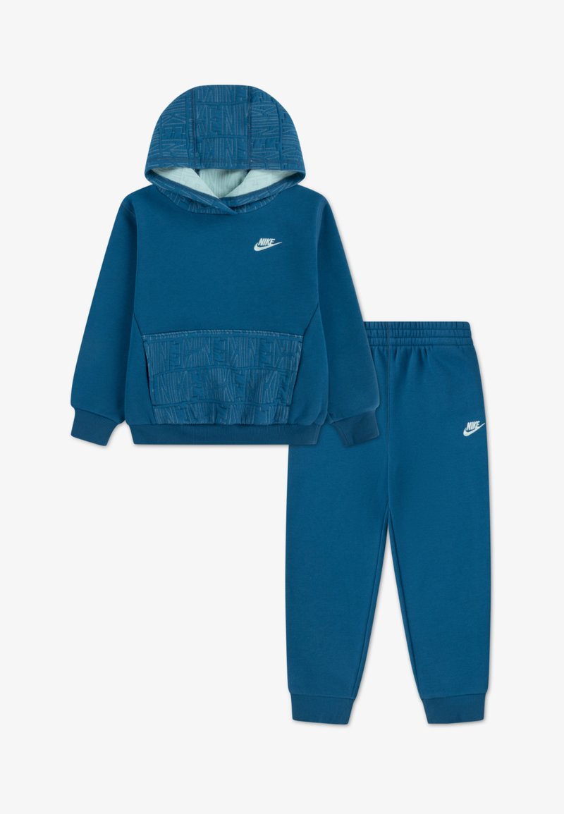 Modrý športový komplekt Nike s kapucňou, ktorý obsahuje textúrovanú prednú vrecko a logo, doplnený o zladené zúžené tepláky.