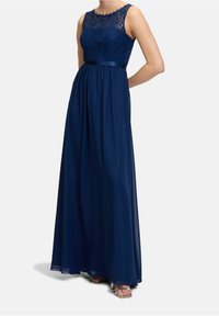 Marinblå aftonklänning med spetstopp, ärmlös design och flödande kjol med satsbyxor och ankellång fåll.