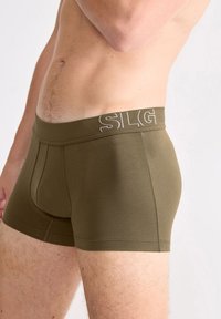 Olivgrüne Boxershorts mit einem weichen, elastischen Bund, der weiße Schriftzüge aufweist, aus einem dehnbaren Baumwollmix für Komfort und Passform.