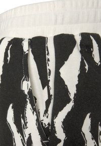Black and white patterned fabric with a ribbed white waistband; features abstract shapes on a textured cotton blend.