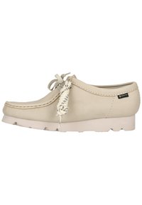 Mocassin en cuir beige avec semelle blanche, lacets décoratifs et étiquette GORE-TEX sur le côté, présenté en profil latéral sur fond blanc.