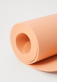 Joga prostirka, narančasta, smotana s teksturiranom površinom, glatkim rubovima i okruglim otvorom u sredini. Prikladna za vježbanje i udobnu upotrebu.