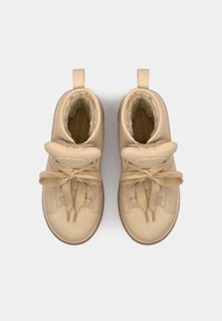 Sneaker alte beige con lacci, fodera in morbido pelliccia, colletto imbottito e suola in gomma. Texture liscia con dettagli cuciti.
