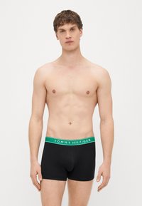 Boxers pretos de algodão com um cós verde. O cós apresenta o logótipo "TOMMY HILFIGER" em destaque.