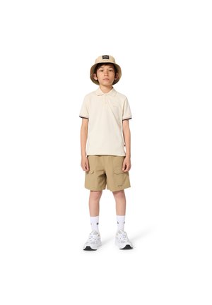 Light beige polo shirt with short sleeves and navy trim, beige cargo shorts with pockets, white socks, and white sneakers, topped with a beige bucket hat.