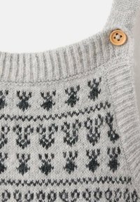 Vêtement en tricot gris avec motifs noirs, bretelles côtelées et un détail en bouton en bois. Tissu texturé avec une finition confortable.