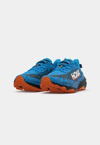 Blue athletic shoes featuring a textured design, black accents, and an orange rubber outsole. HOKA branding is visible on the side.