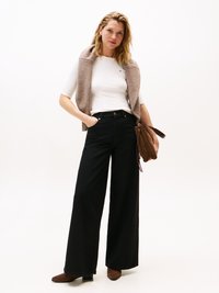 Sorte vidde jeans, hvit tettsittende skjorte, lys brun strikket vest, brune hæl støvler og en brun skulderveske. Minimalistisk design, uten mønstre.