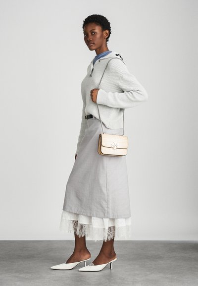 Light gray knitted sweater, layered over a blue shirt, paired with a gray skirt featuring a lace hem. White mules and a small gold-accented handbag.