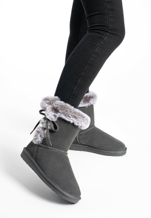 Botines de ante gris con un suave cuello de pelaje sintético gris, atados con un lazo y una suela de goma plana para mayor comodidad.