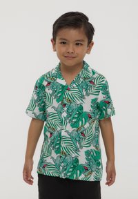 Camicia a maniche corte con bottoni, caratterizzata da una stampa di dinosauri verdi su sfondo bianco con foglie tropicali. Tessuto leggero e vestibilità comoda.