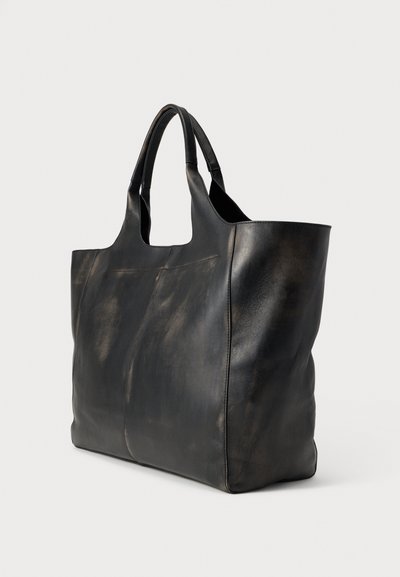 Sort lædertaske med glat tekstur, minimalistisk design, korte håndtag og subtile variationer i glans. Ingen synlige metaldele eller pynt.