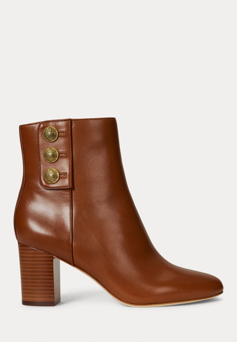 Rjavi usnjeni gležnjarji s koničastim nosom in zloženim petnim delom. Zunaj imajo tri zlate gumbke. Gladka tekstura.