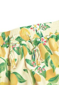 Korte broek met citroenpatroon, een zachte, elastische tailleband en decoratieve kwastjes, met levendige gele citroenen en groene bladeren op een crèmekleurige achtergrond.