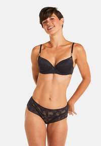 Ensemble de lingerie en dentelle noire comprenant un soutien-gorge moulé avec des bretelles réglables et des éléments décoratifs, associé à un culotte taille haute assortie.