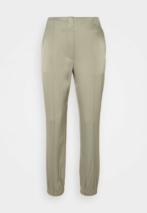 Beigenväriset slim-fit-housut korkealla vyötäröllä, etuosan saumalisteillä ja nilkkojen kohdalla elastisilla resoreilla.