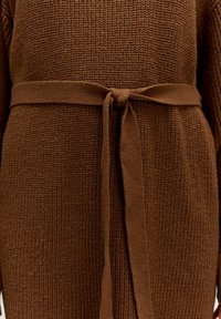 Brauner Strickartikel mit strukturiertem Oberflächenmaterial, gebundenem Taillengürtel und weiten Ärmeln. Der Stoff hat ein weiches, gemütliches Aussehen.