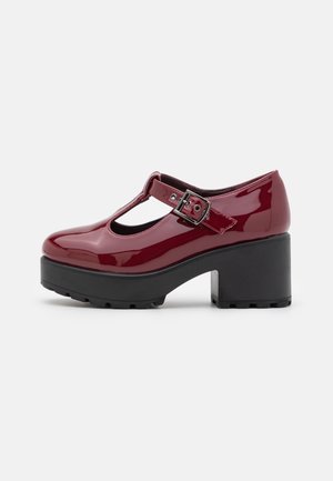 Chaussure Mary Jane brillante couleur bordeaux avec bride à boucle, semelle plateforme noire épaisse et talon bloc, vue de côté sur fond blanc.