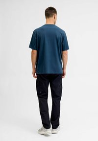 Krótki rękaw, granatowy t-shirt z okrągłym dekoltem, w połączeniu z czarnymi spodniami cargo z bocznymi kieszeniami i luźnym fasonem.