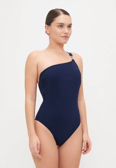 Marineblå helkroppsbikini med asymmetrisk halsringning, en skulderstropp og rynkedetalj på siden. Laget av glatt, elastisk stoff.