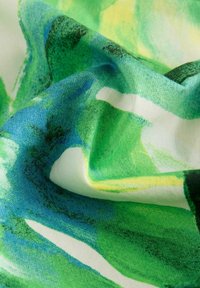 Tela multicolorida con patrones abstractos en verde y azul con acentos en amarillo. La textura parece suave y ligera.