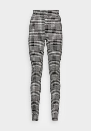 Czarno-białe legginsy w kratę z wysokim stanem. Materiał posiada teksturowany wzór z kontrastującymi kratkami i wzorem houndstooth.