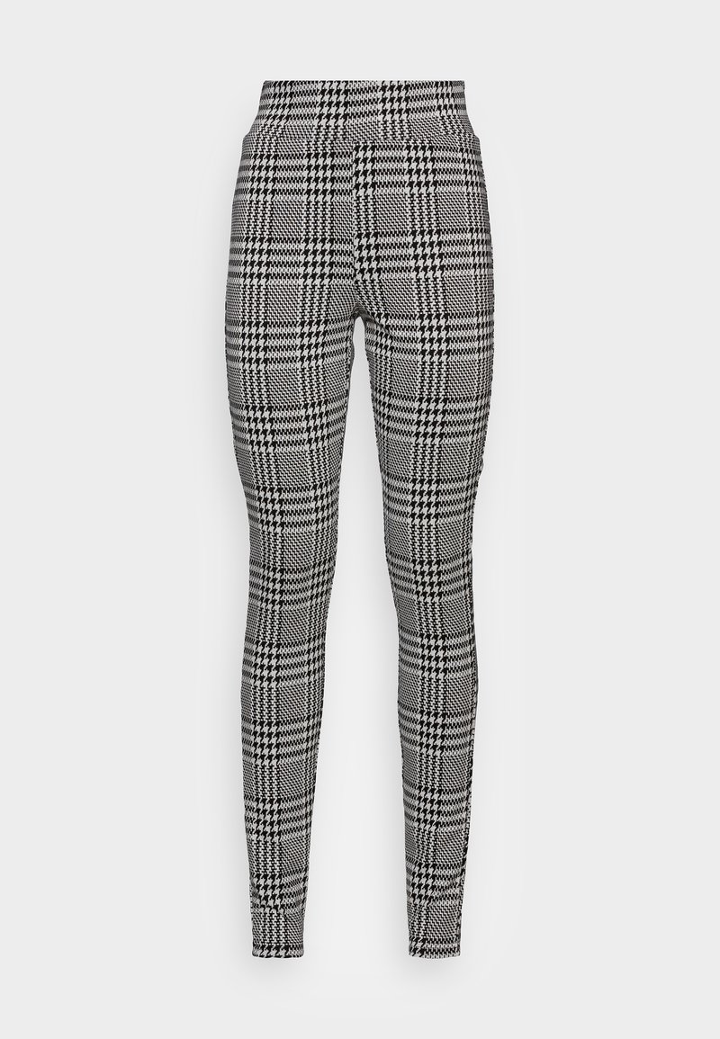 Leggings à carreaux noir et blanc avec taille haute. Le tissu présente un motif texturé avec des carreaux contrastants et un design pied-de-poule.
